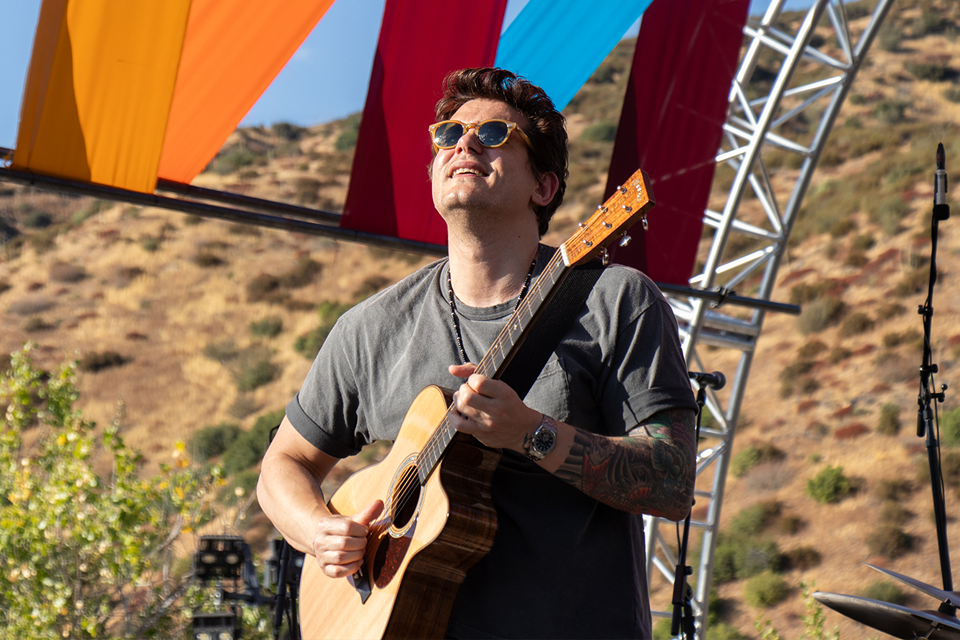 John Mayer playing his guitar on stage