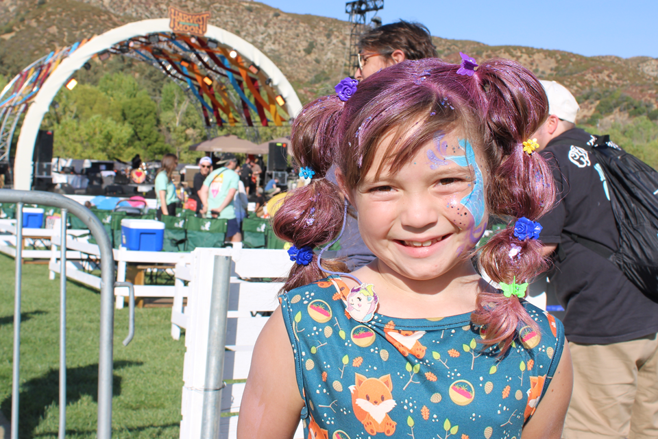 Smiling girl with face paint, stage in background