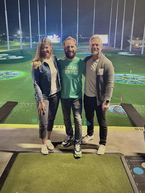 Three friends pose for a photo at Topgolf