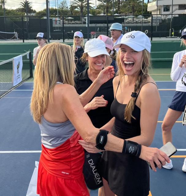 Two women embrace with big smiles on the court after learning one has just won 3rd place! 