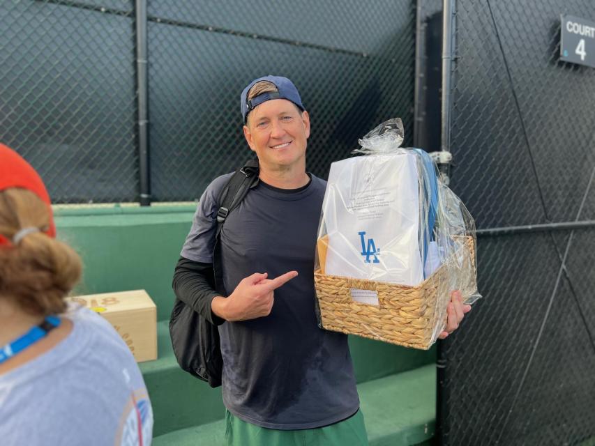 Pickleball winner poses with his dodgers prize basket. 