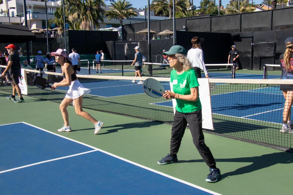 A woman in a green shirt waits for the pickleball to come her way! 