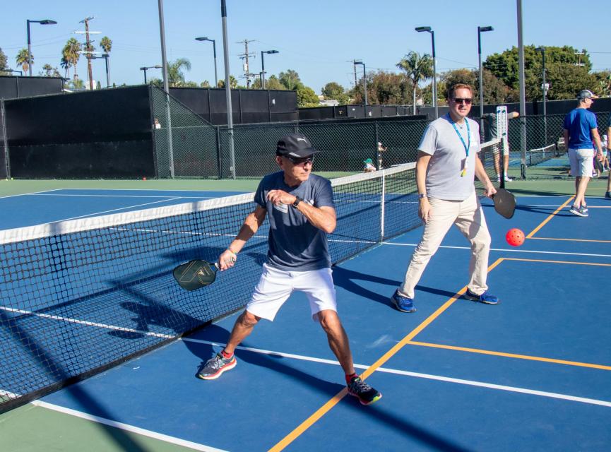 Two players return the pickleball to their opponents. 