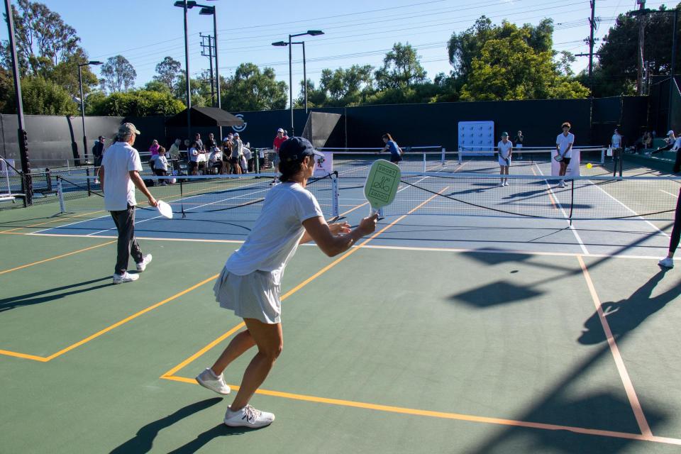 A pickleball player photographed from behind  prepares to return the ball  across the net. 