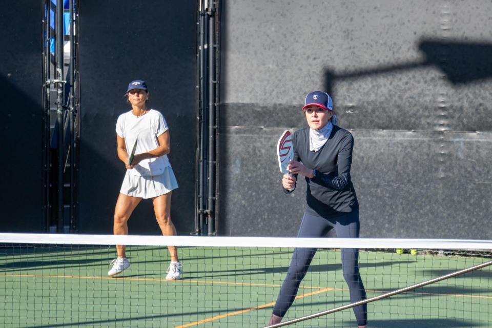 Two women wait to return the serve of the pickleball. 